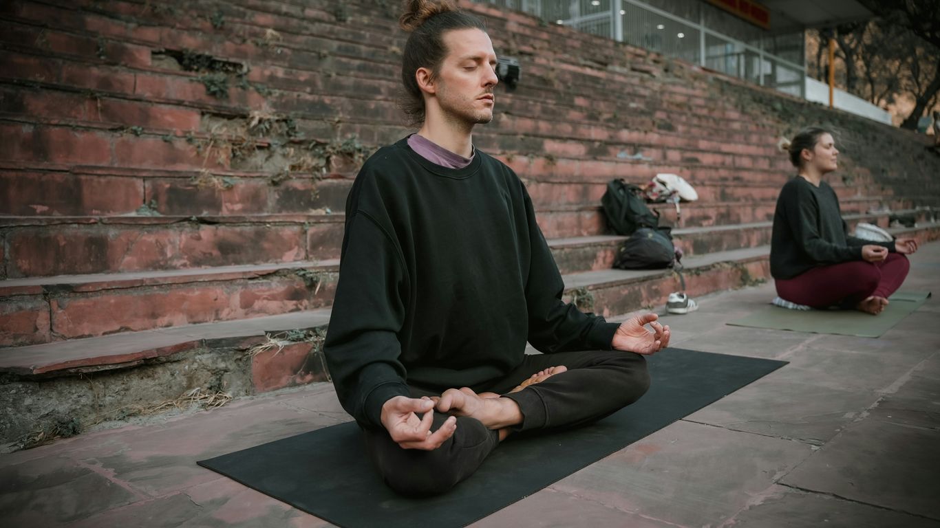 a man sitting on a yoga mat in front of a brick wall