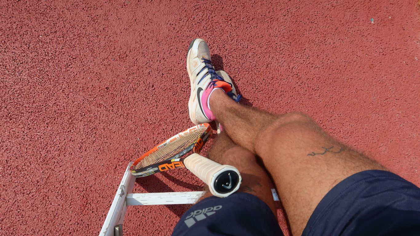 A tennis player rests on the court.