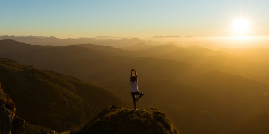 woman stretching on mountain top during sunrise