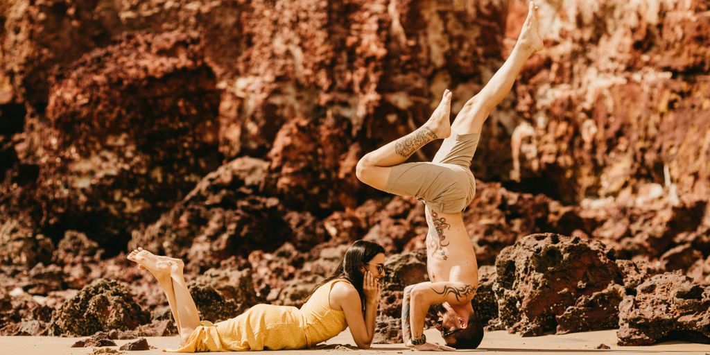 photography of woman lying on sand in front of man during daytime