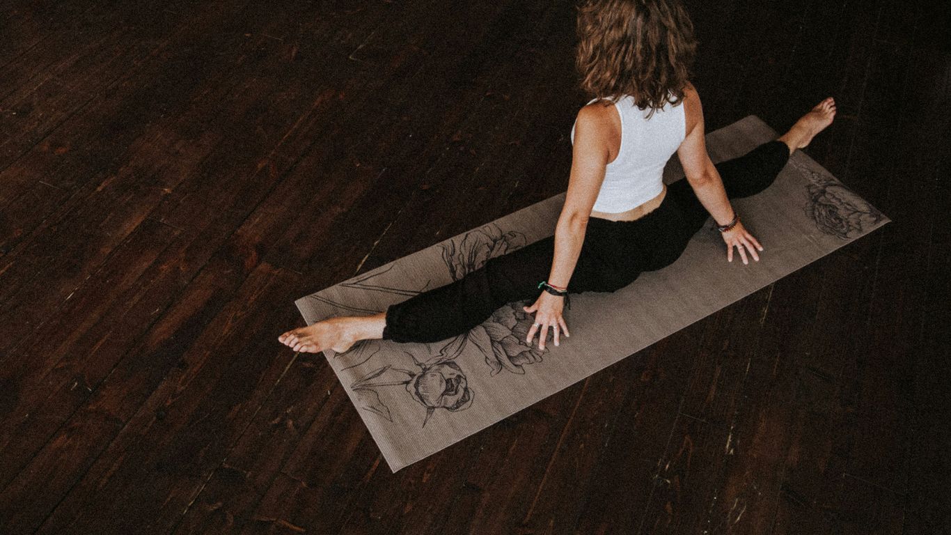 woman in white crop-top and black leggings doing yoga