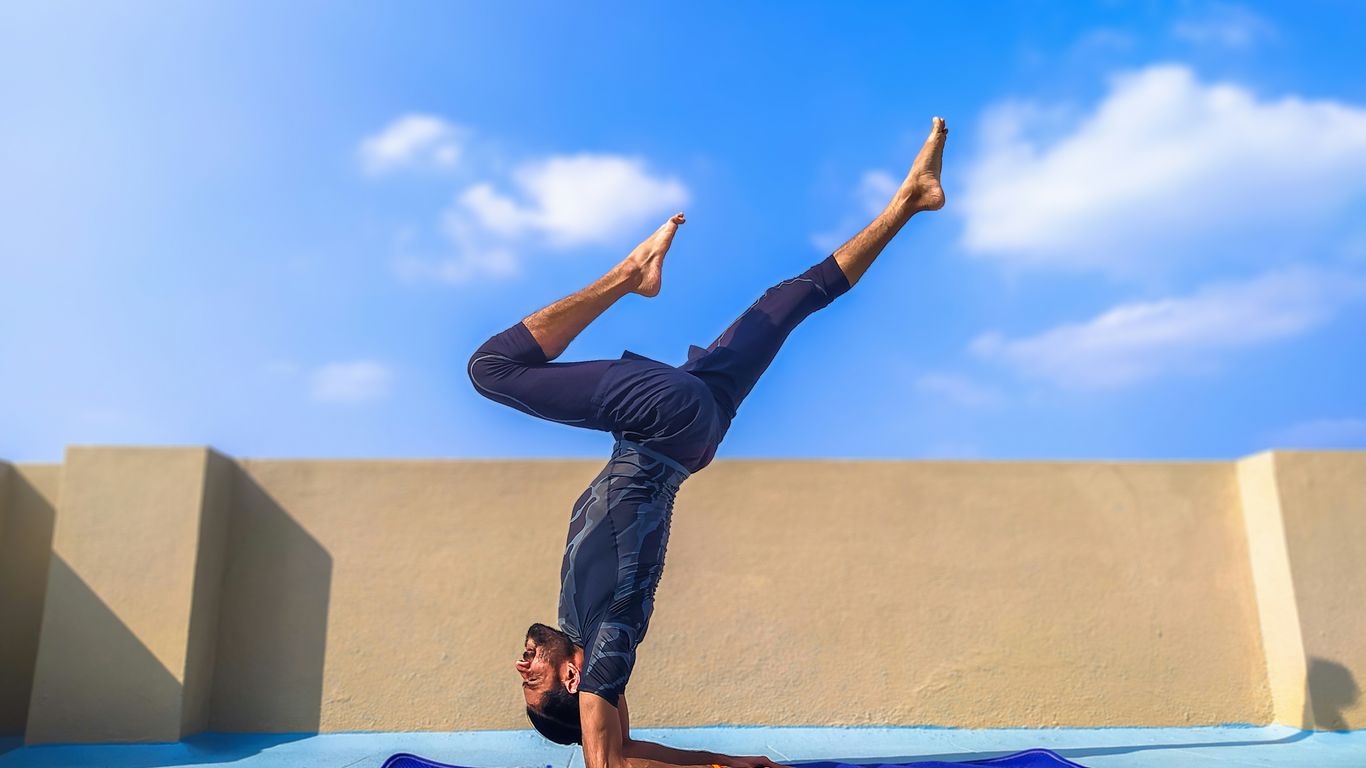 man in black pants and black shirt standing on blue yoga mat