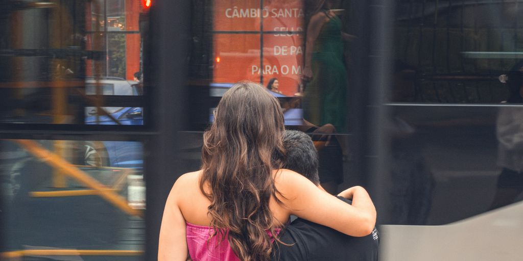 A couple hugs each other while waiting outside.