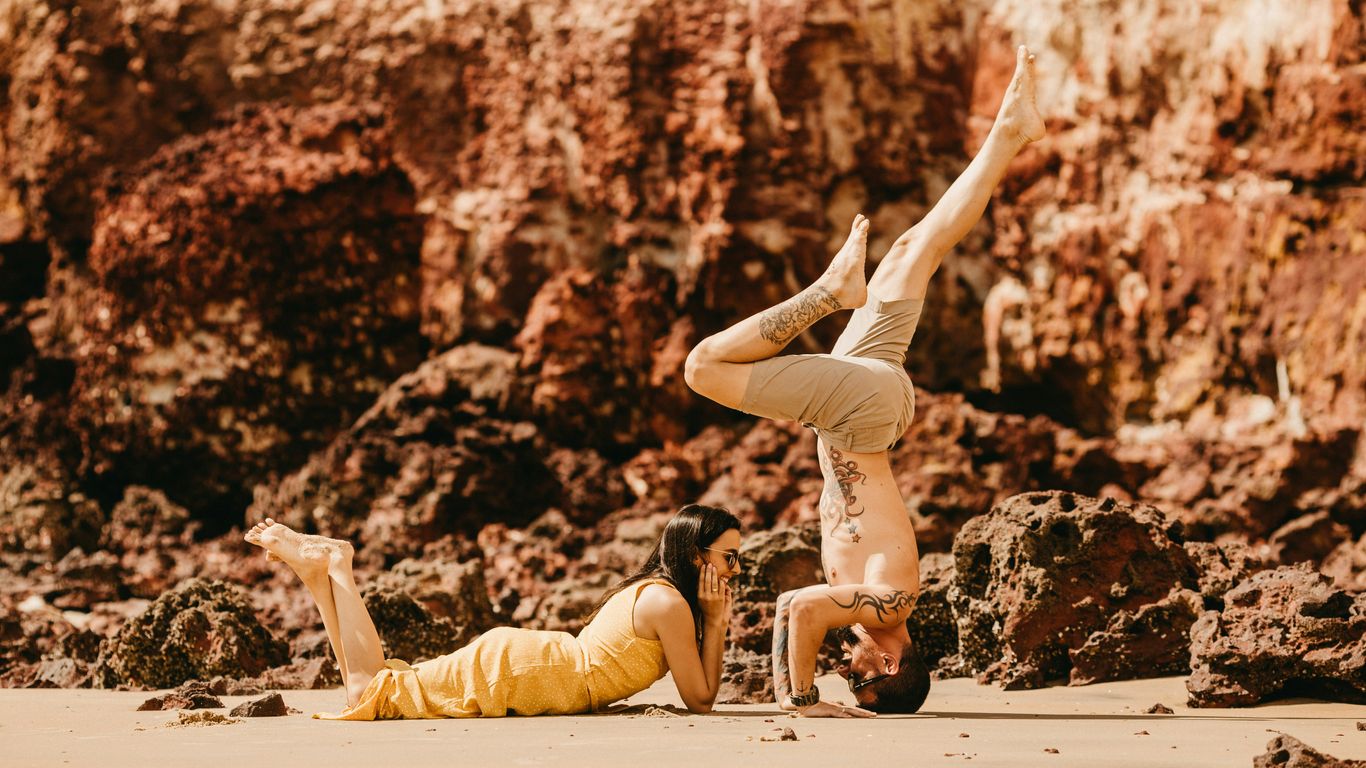 photography of woman lying on sand in front of man during daytime