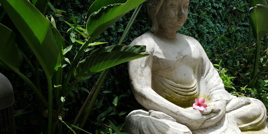 white concrete statue near green plants during daytime