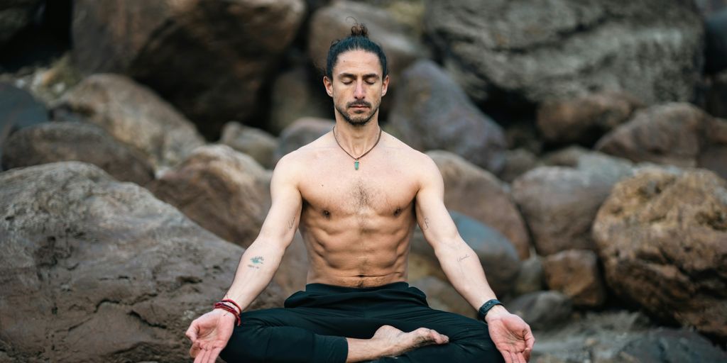 a man sitting on a rock doing yoga
