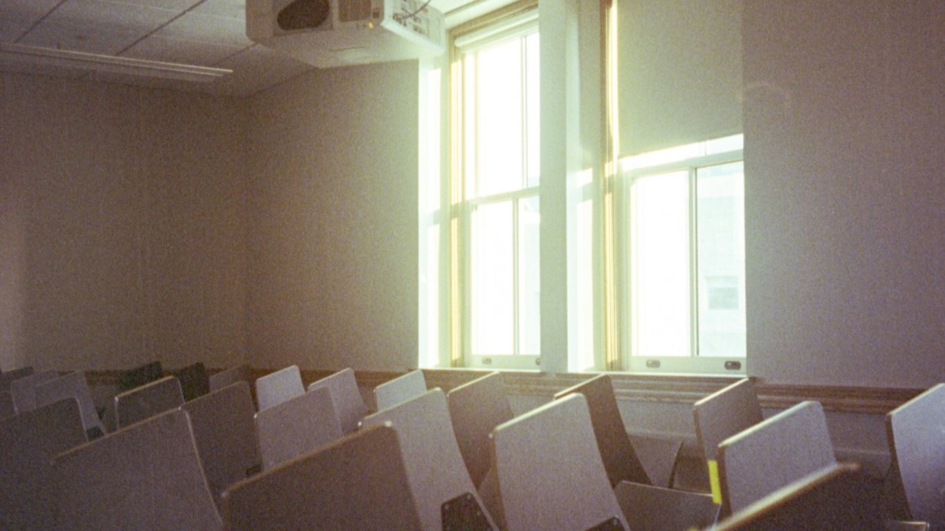 A room filled with lots of white chairs next to a window
