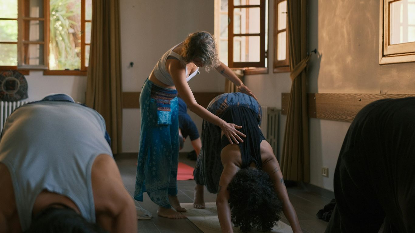 Yoga instructor assisting student in downward dog pose.