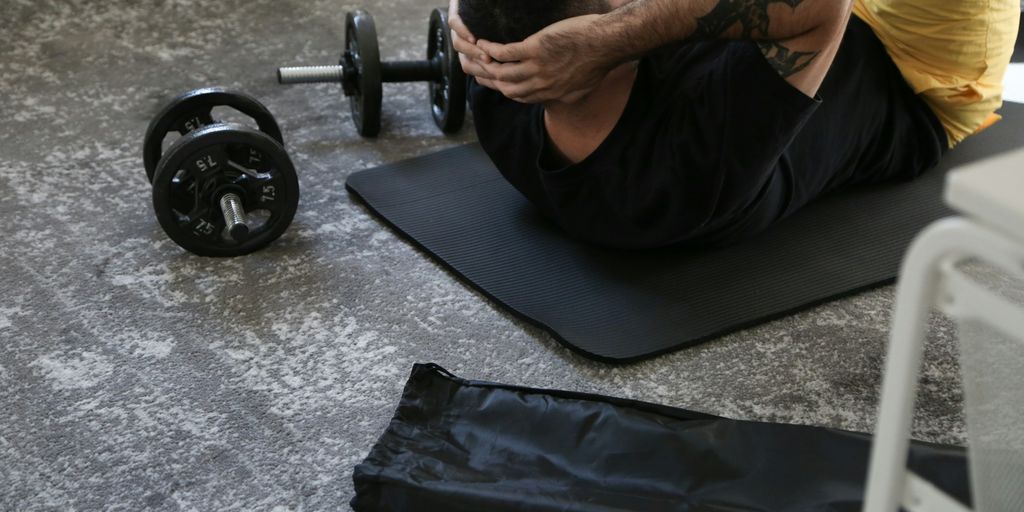 a man is doing exercises on a mat with a barbell