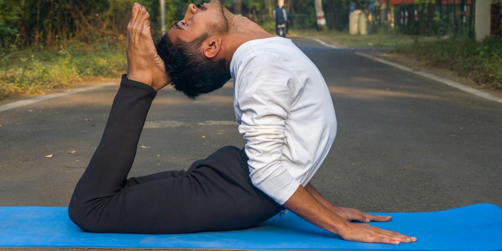 A man sitting on a blue mat in the middle of the road