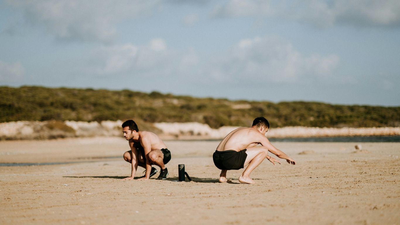 two men sitting on sand