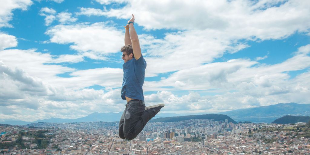 woman in blue tank top and blue denim jeans standing on top of building during daytime