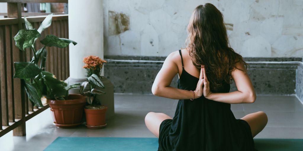 woman wearing black shirt sitting on green yoga mat