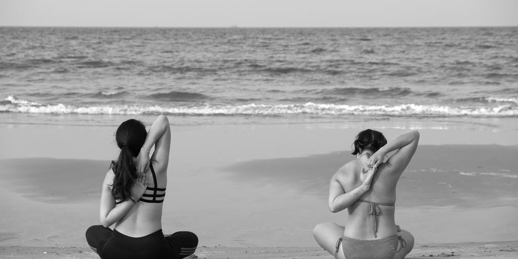 grayscale photography unknown persons seating near body of water