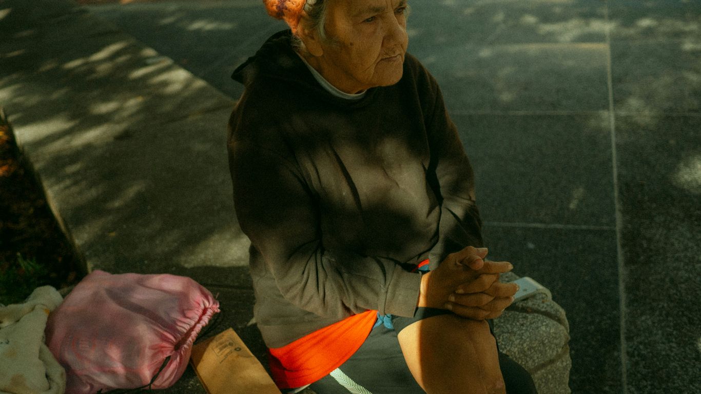 A woman sitting on a curb with her hand on her knee