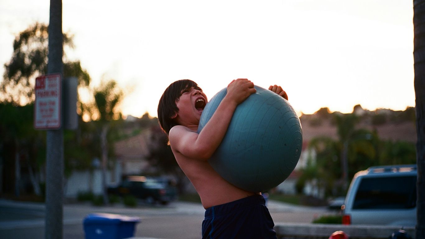 boy's hugging yoga ball while opening mouth