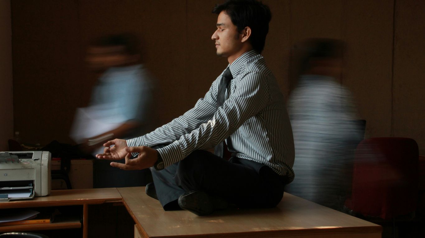 man in white and blue pinstripe dress shirt sitting on brown wooden table