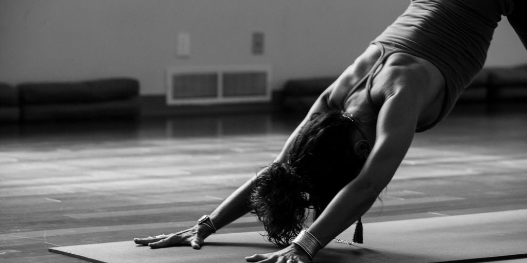 woman in black tank top and black pants bending her body on floor