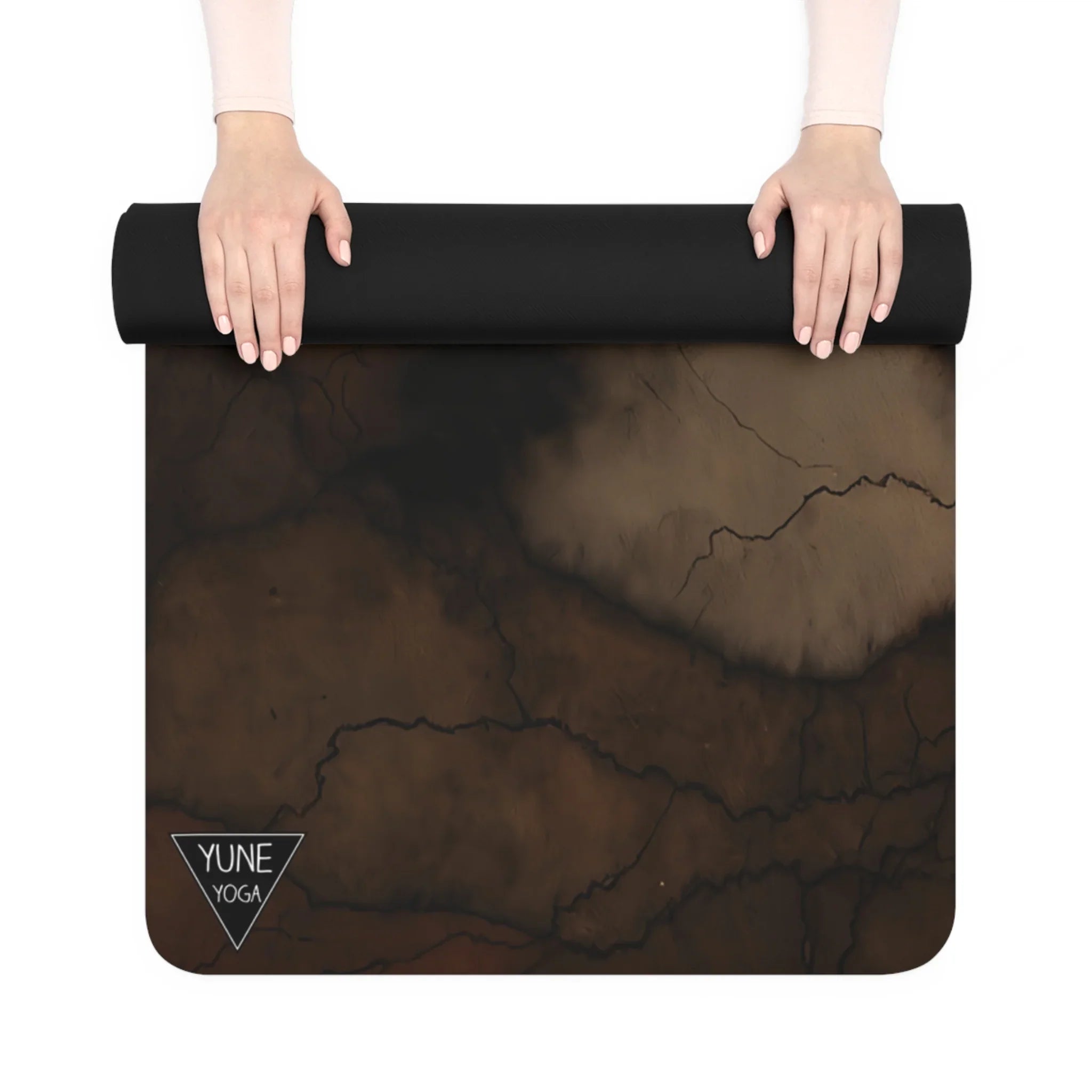 Person rolling out a black and brown marble-pattern yoga mat with Yune Yoga logo