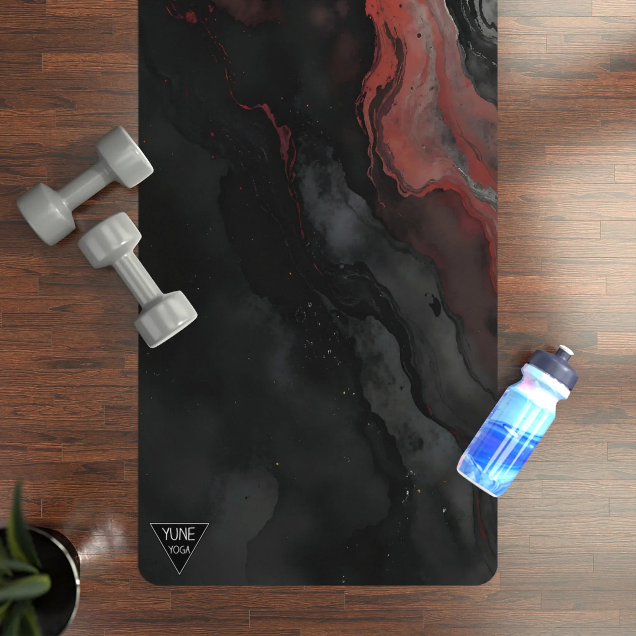 Marble-pattern yoga mat with gray dumbbells and blue water bottle on wood floor