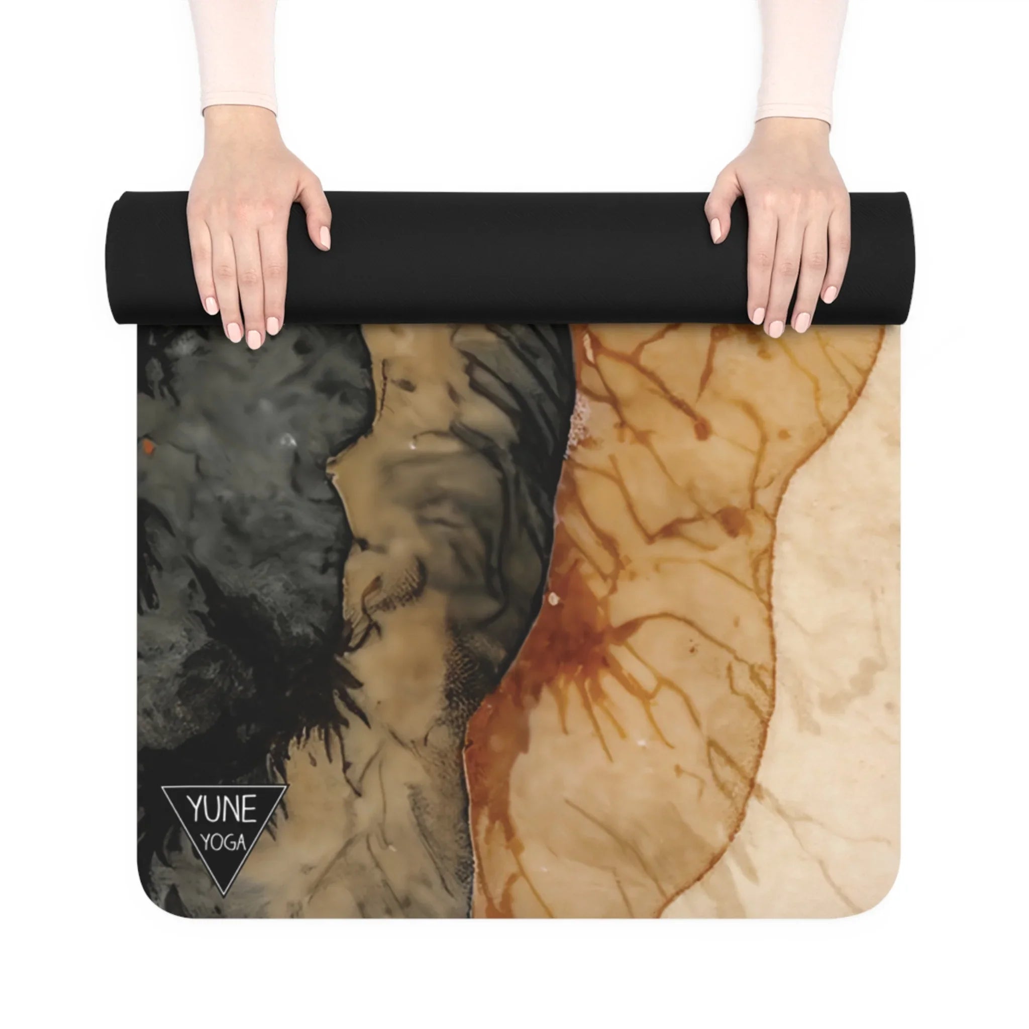 Hands rolling up an abstract black and tan yoga mat with artistic marble design