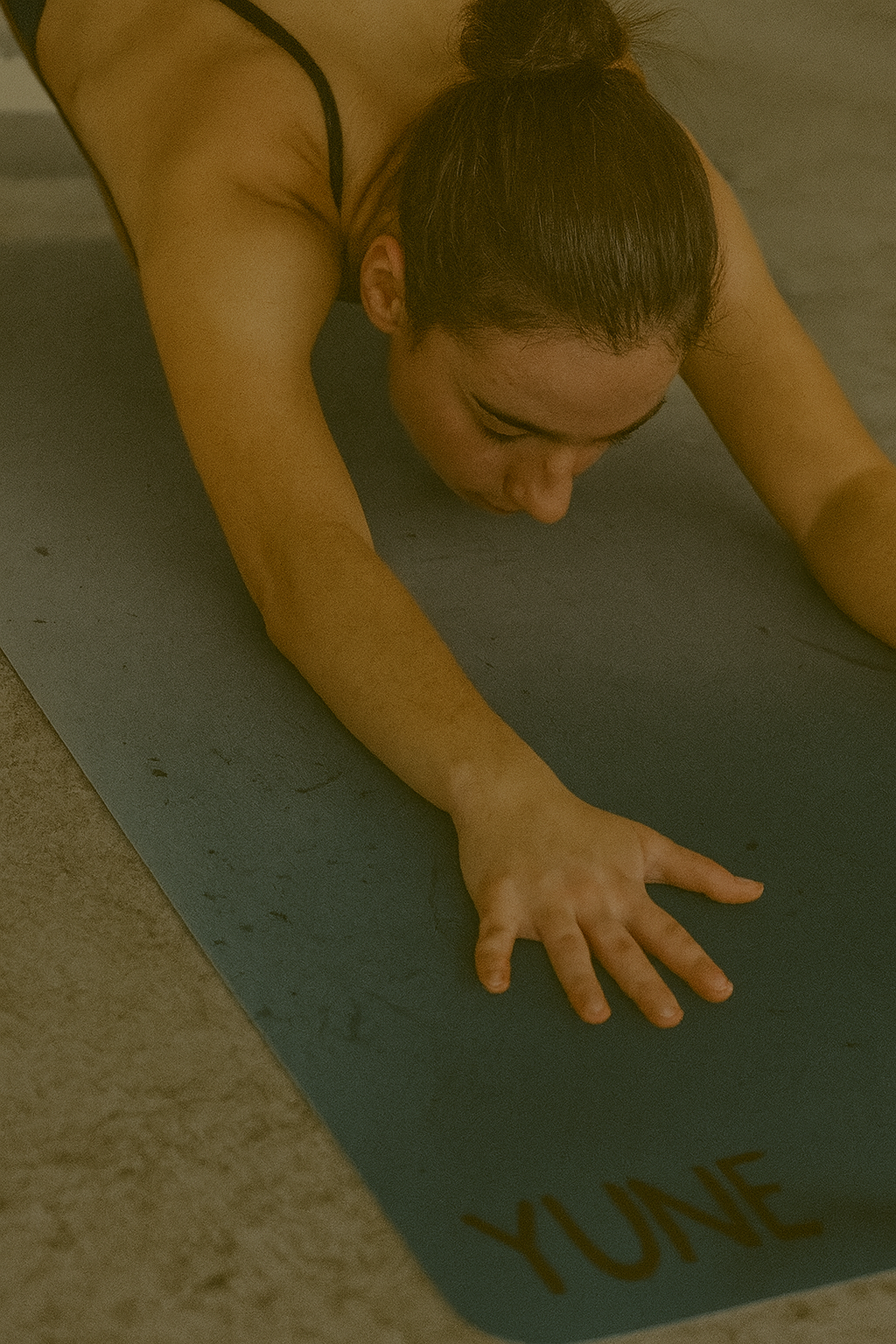 Person on a yoga mat with 'YUNE' branding in a dimly lit setting