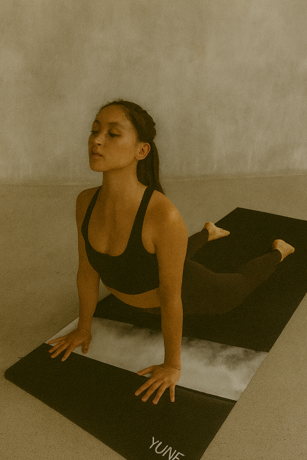 Woman practicing yoga on a mat with a neutral background