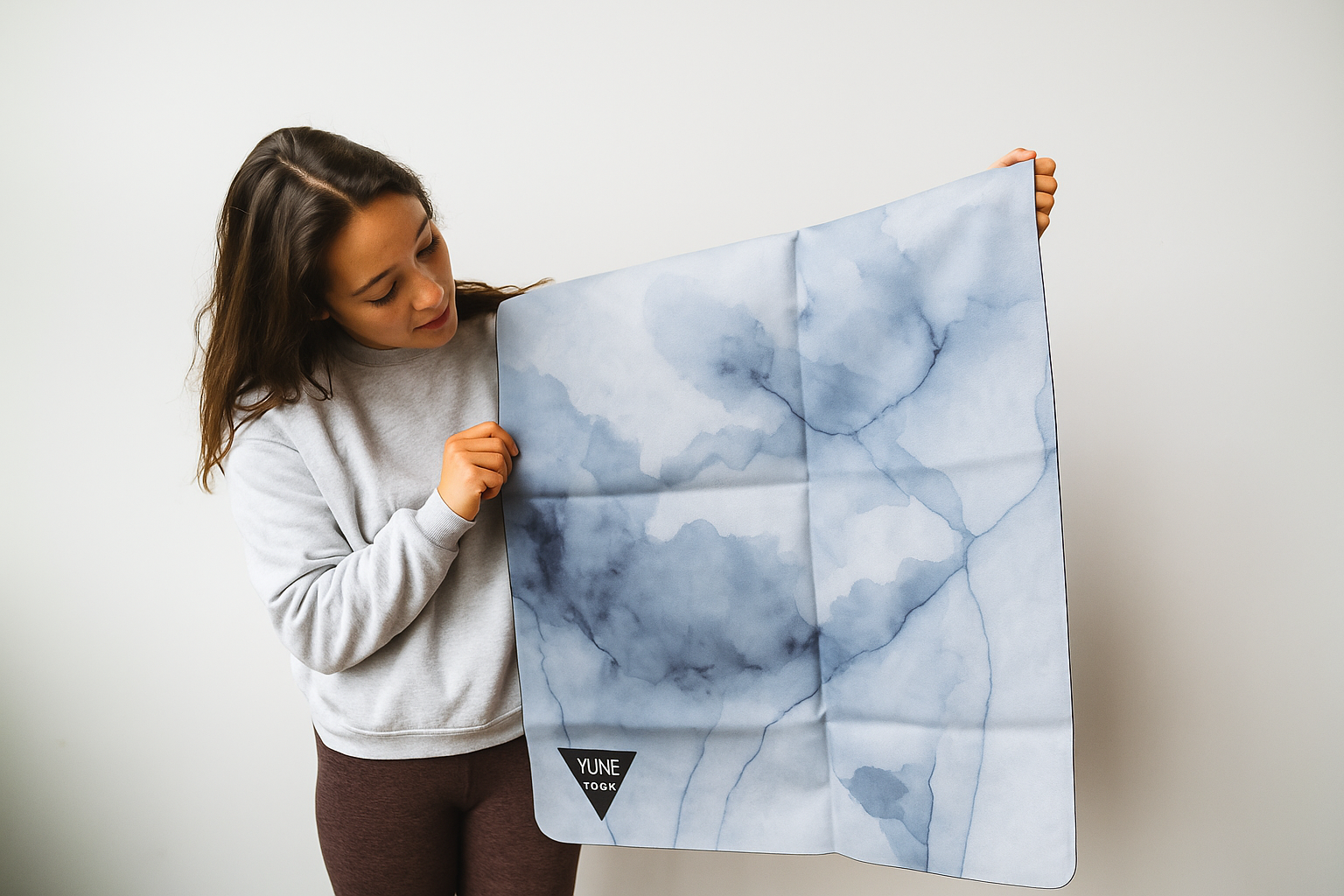 Woman holding a blue and gray marble-patterned mat against a white background