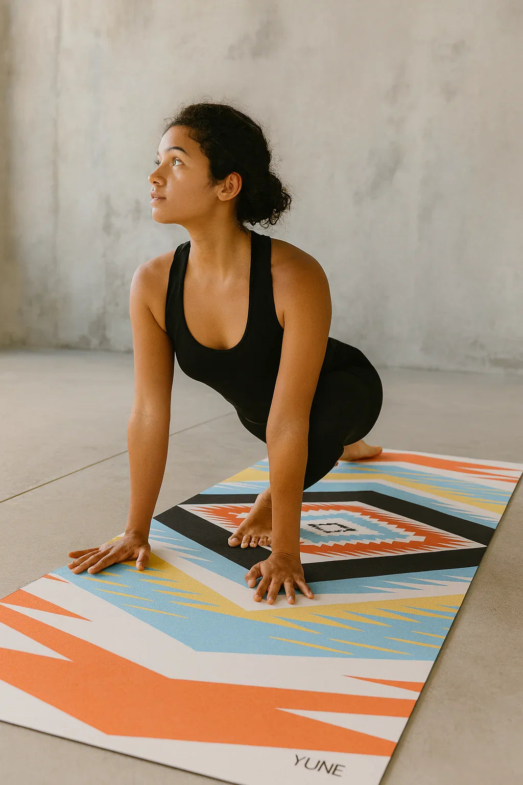 Woman in a yoga pose on a colorful yoga mat with a neutral background