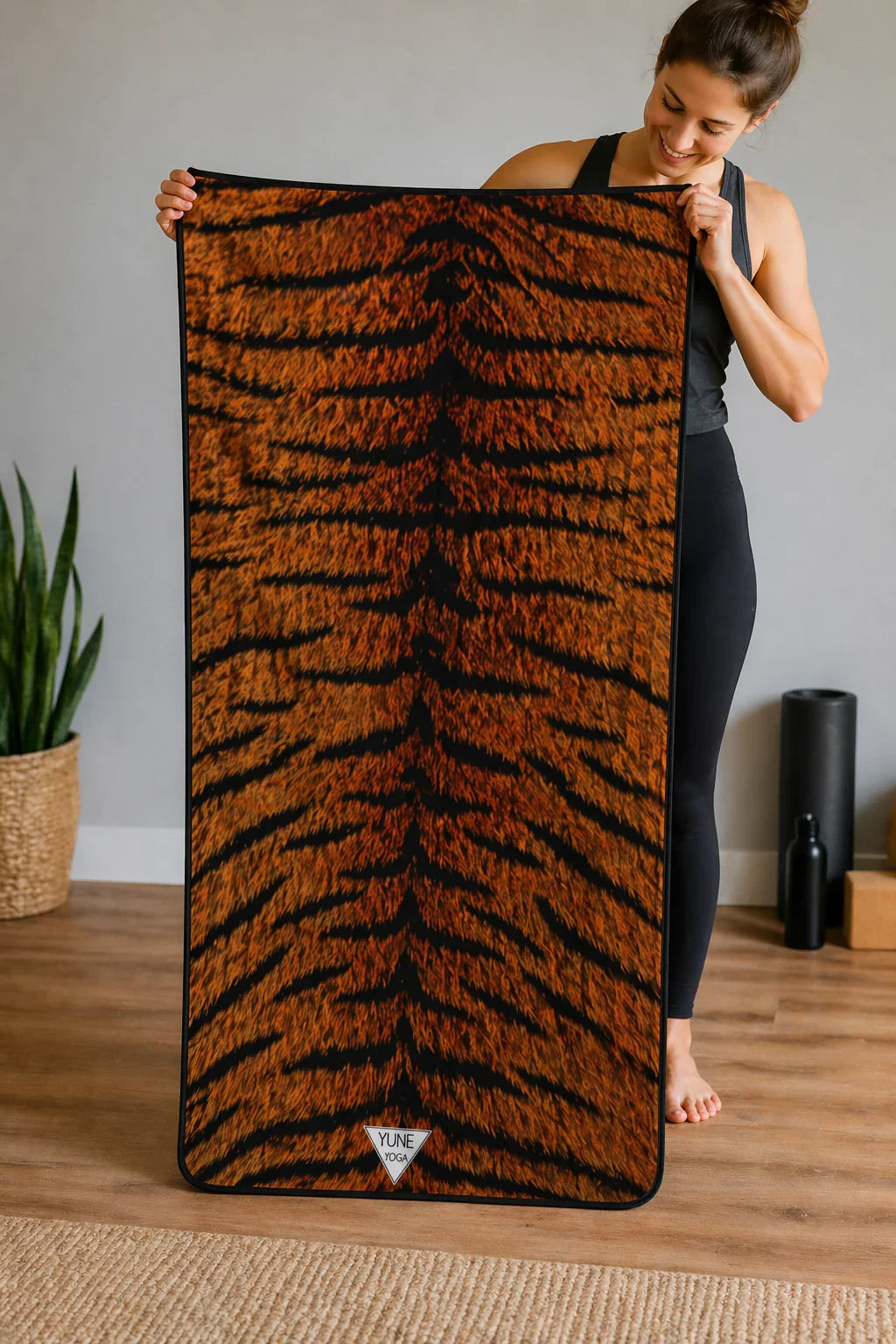Woman holding tiger print yoga towel in modern home studio setting