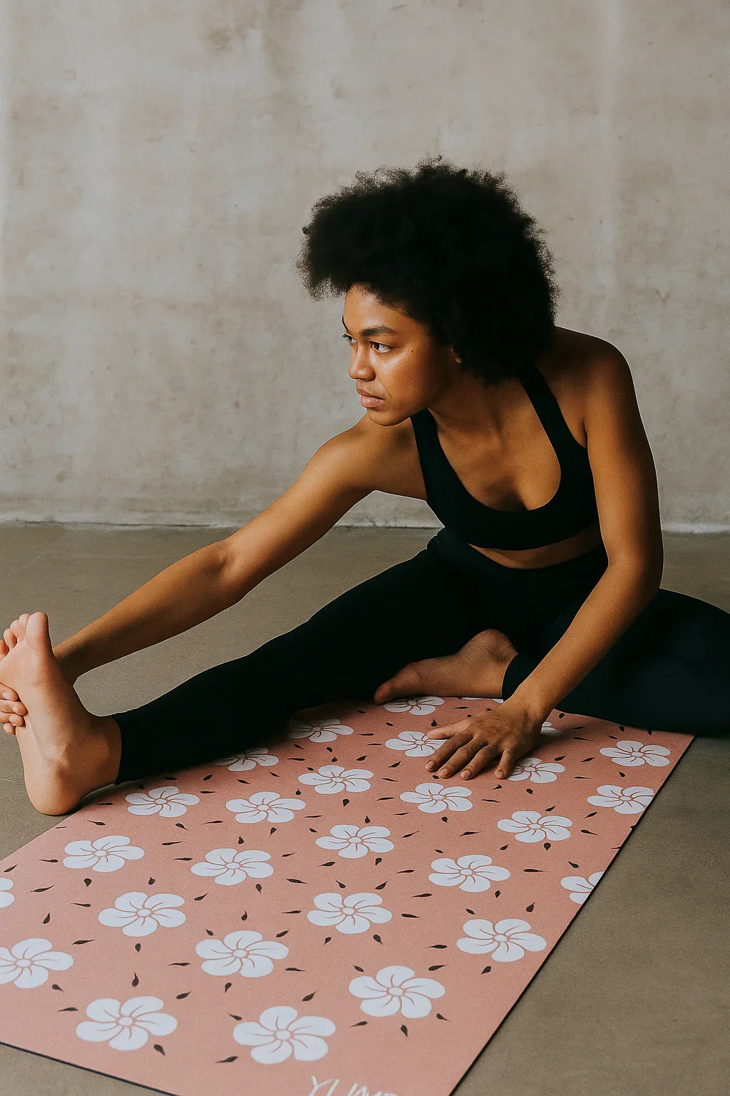 Person stretching on a pink floral yoga mat against a neutral wall.