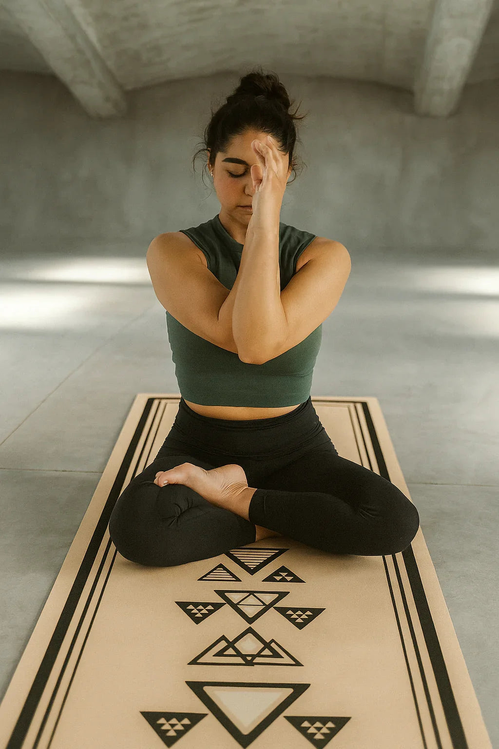Woman practicing yoga on a mat with geometric design in a minimalistic room.