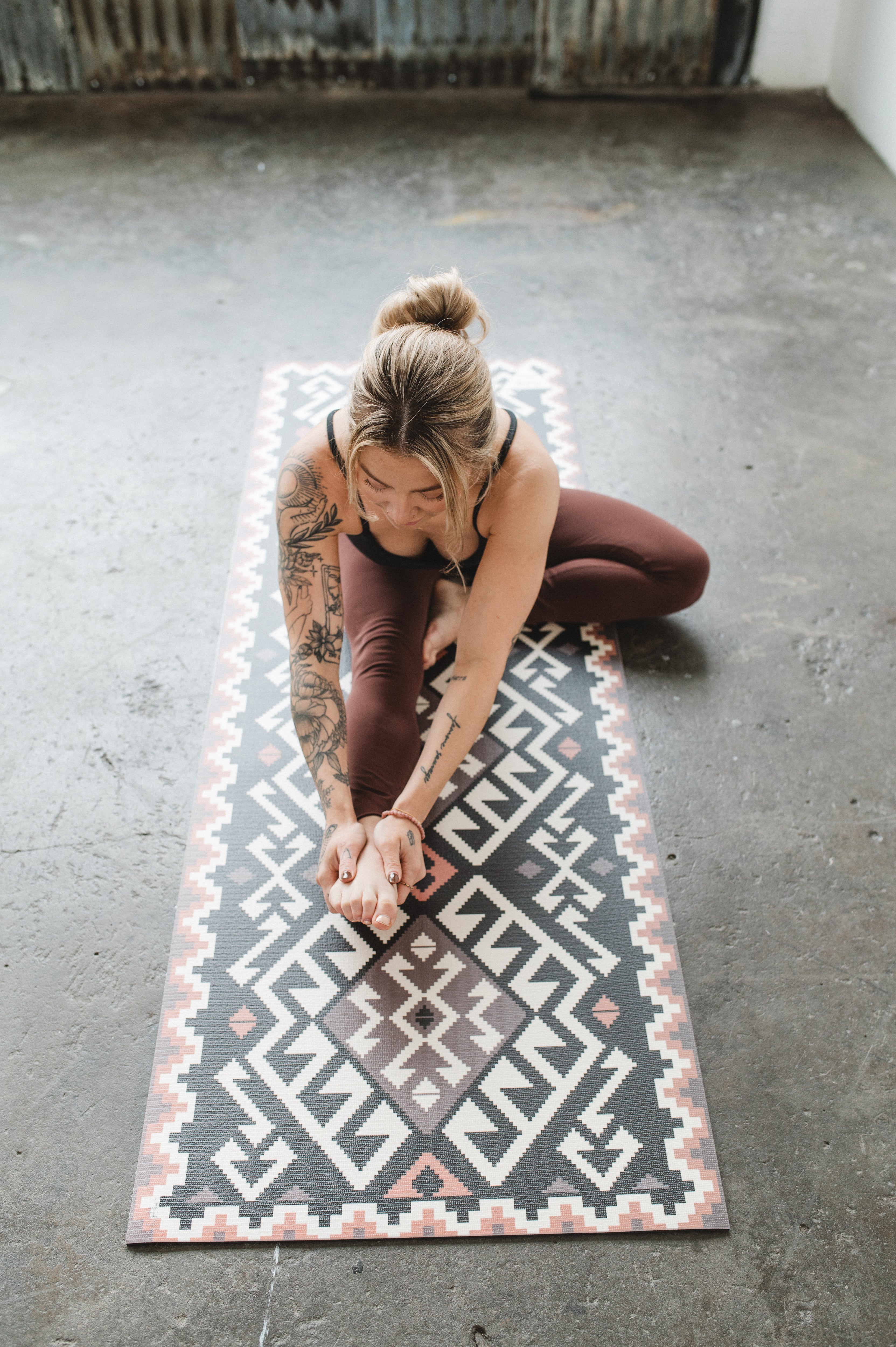 Woman practicing yoga on a patterned mat in an indoor setting