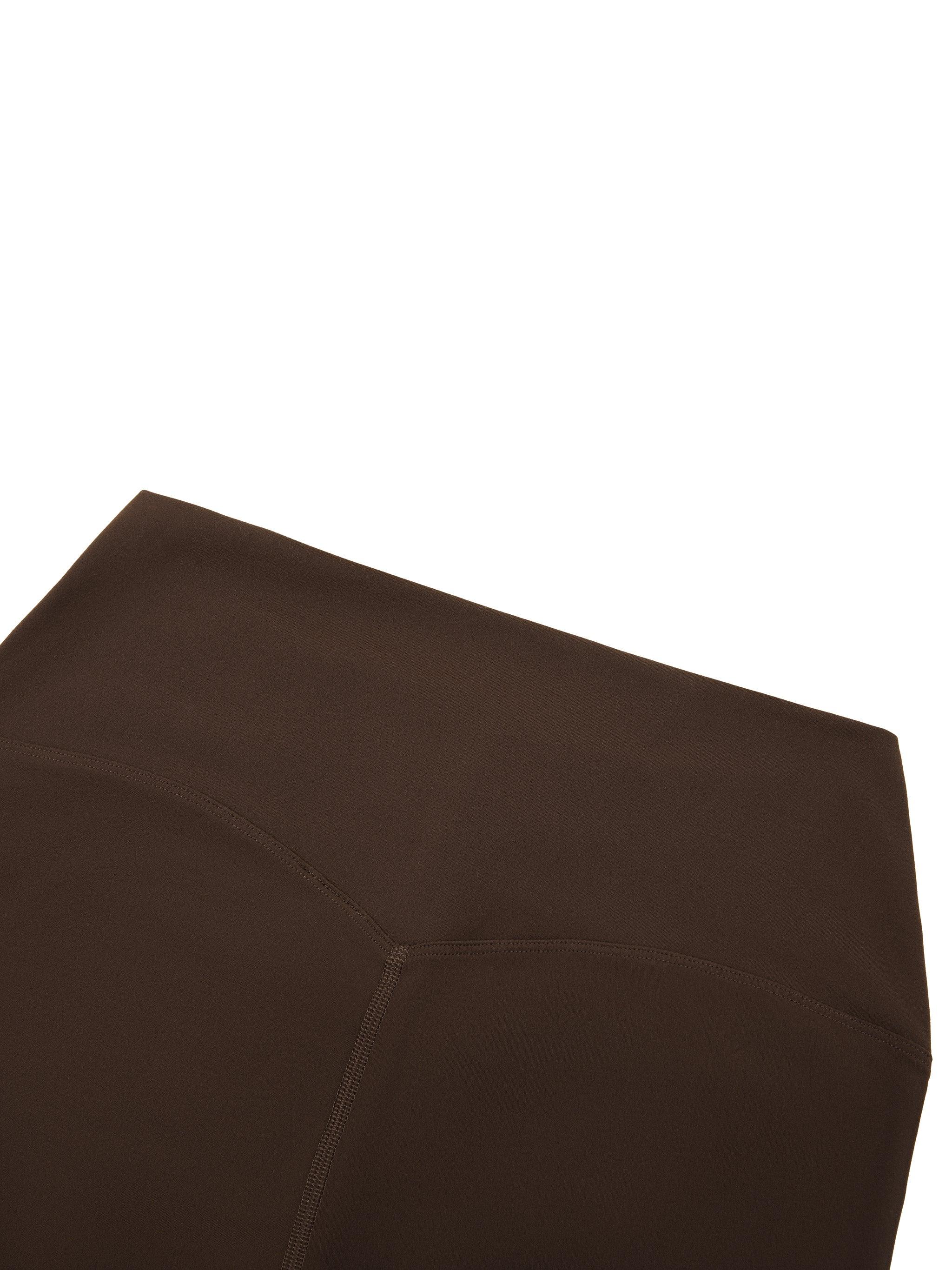 Close-up of brown high-waisted yoga leggings with seam detail on white background