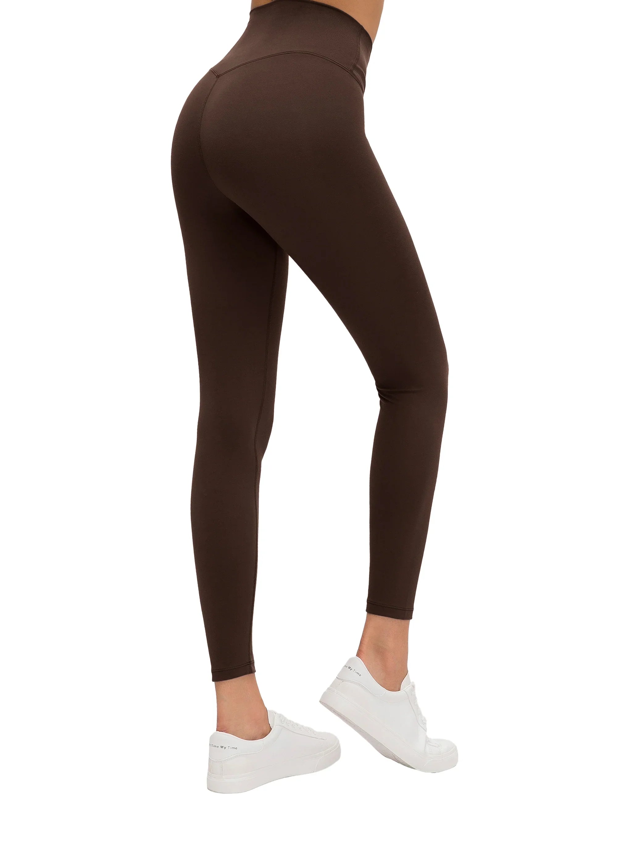 Woman wearing high-waisted brown yoga leggings and white sneakers