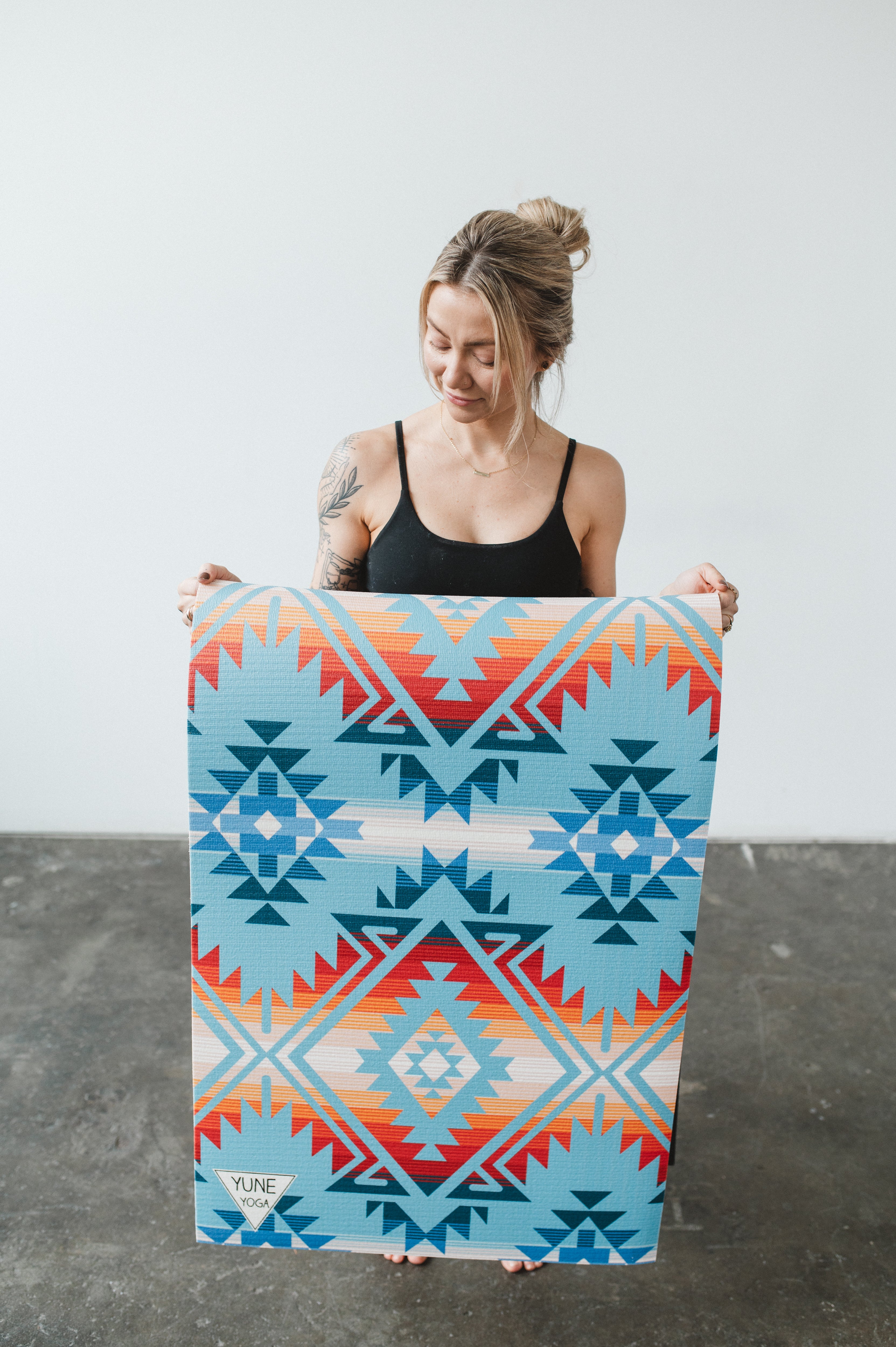 Woman holding a colorful patterned towel against a plain background