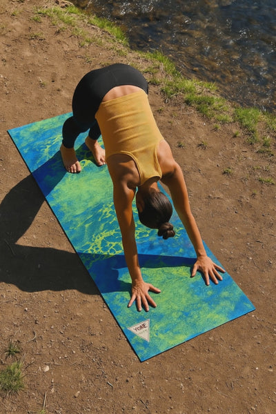 Person doing a yoga pose on a water pattern yoga mat down by the river