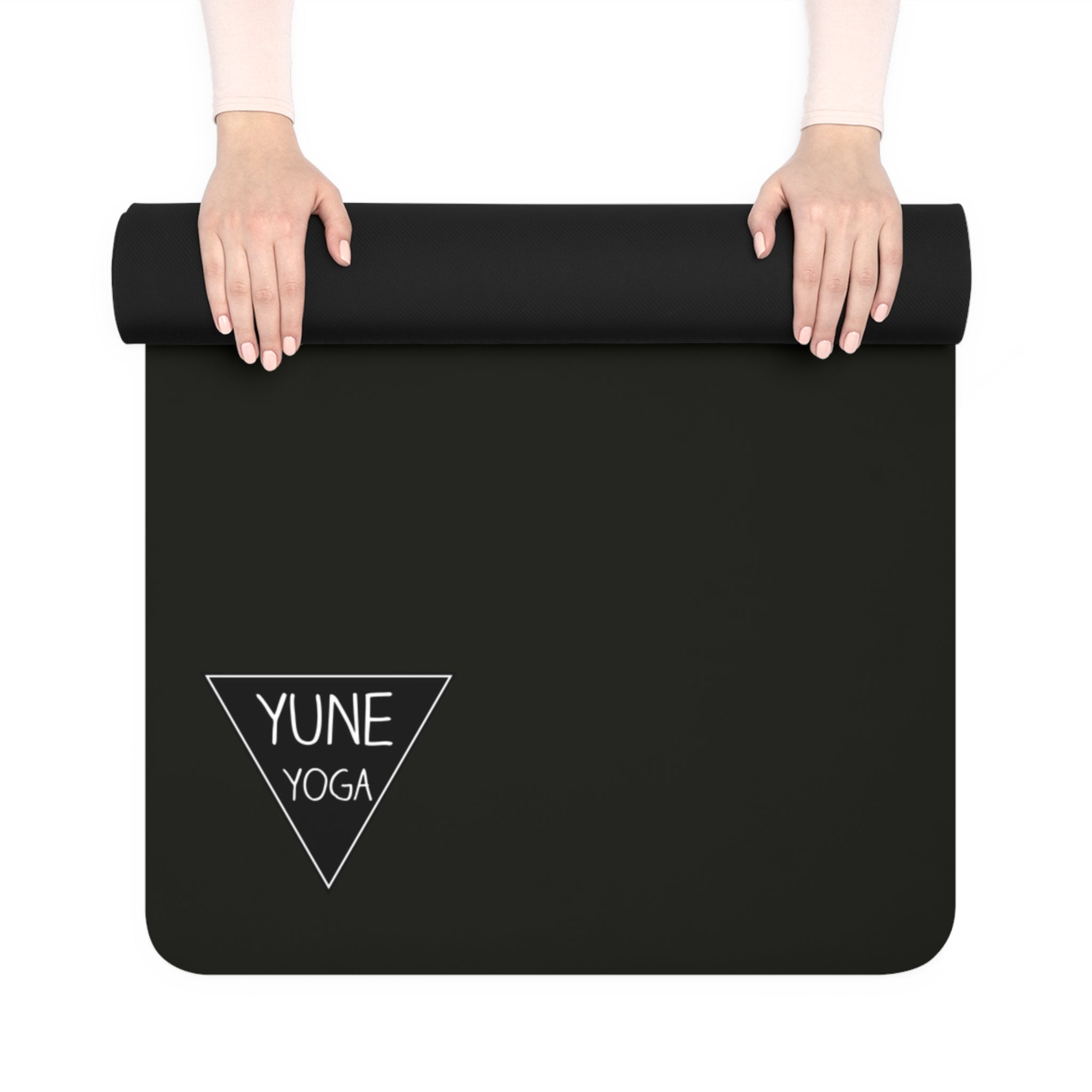Black yoga mat with 'YUNE YOGA' logo held by hands on a white background