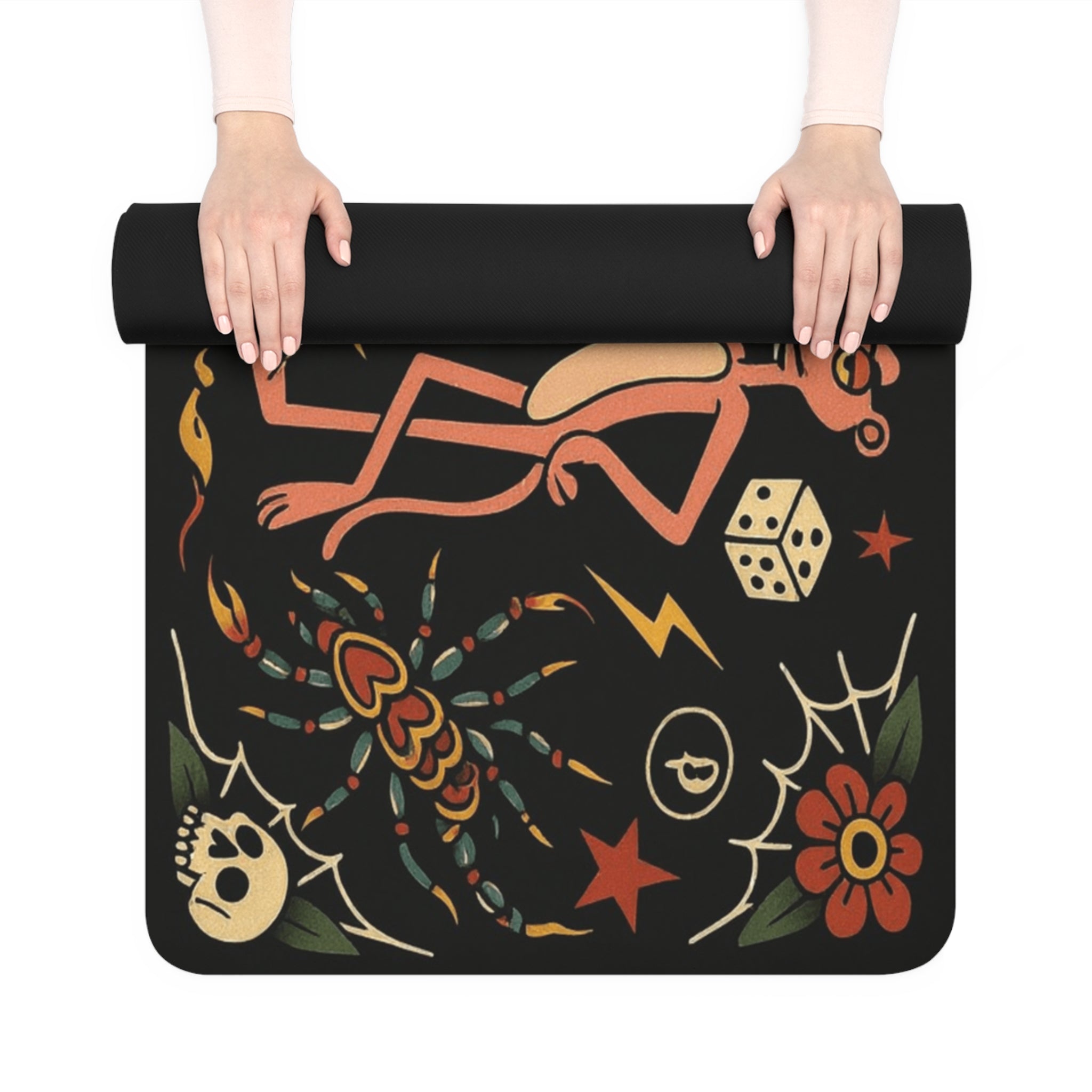 Black mat with colorful designs including a bow, dice, spider, skull, and flower held by hands on a white background