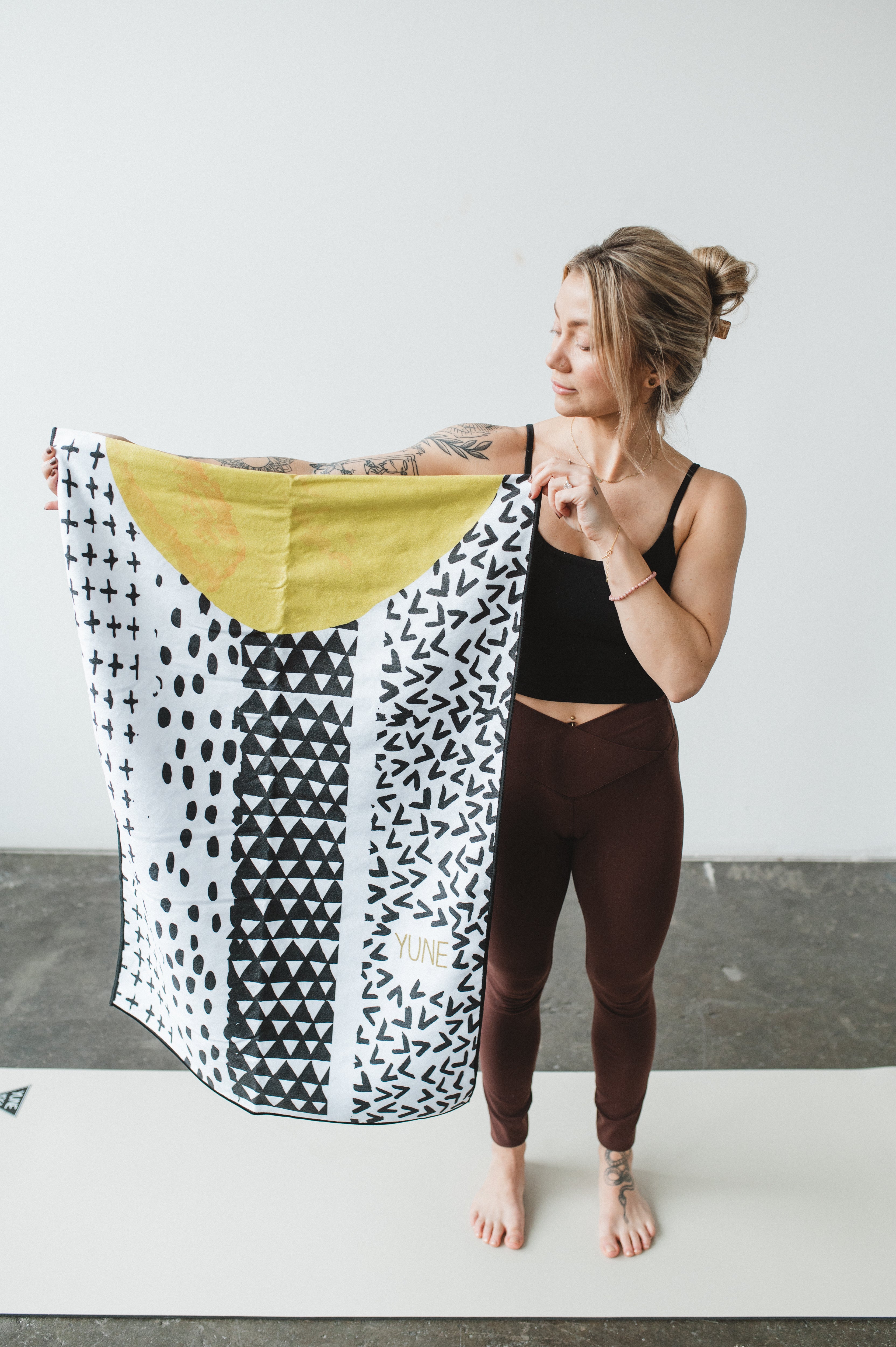 Woman holding a patterned yoga mat on a white background